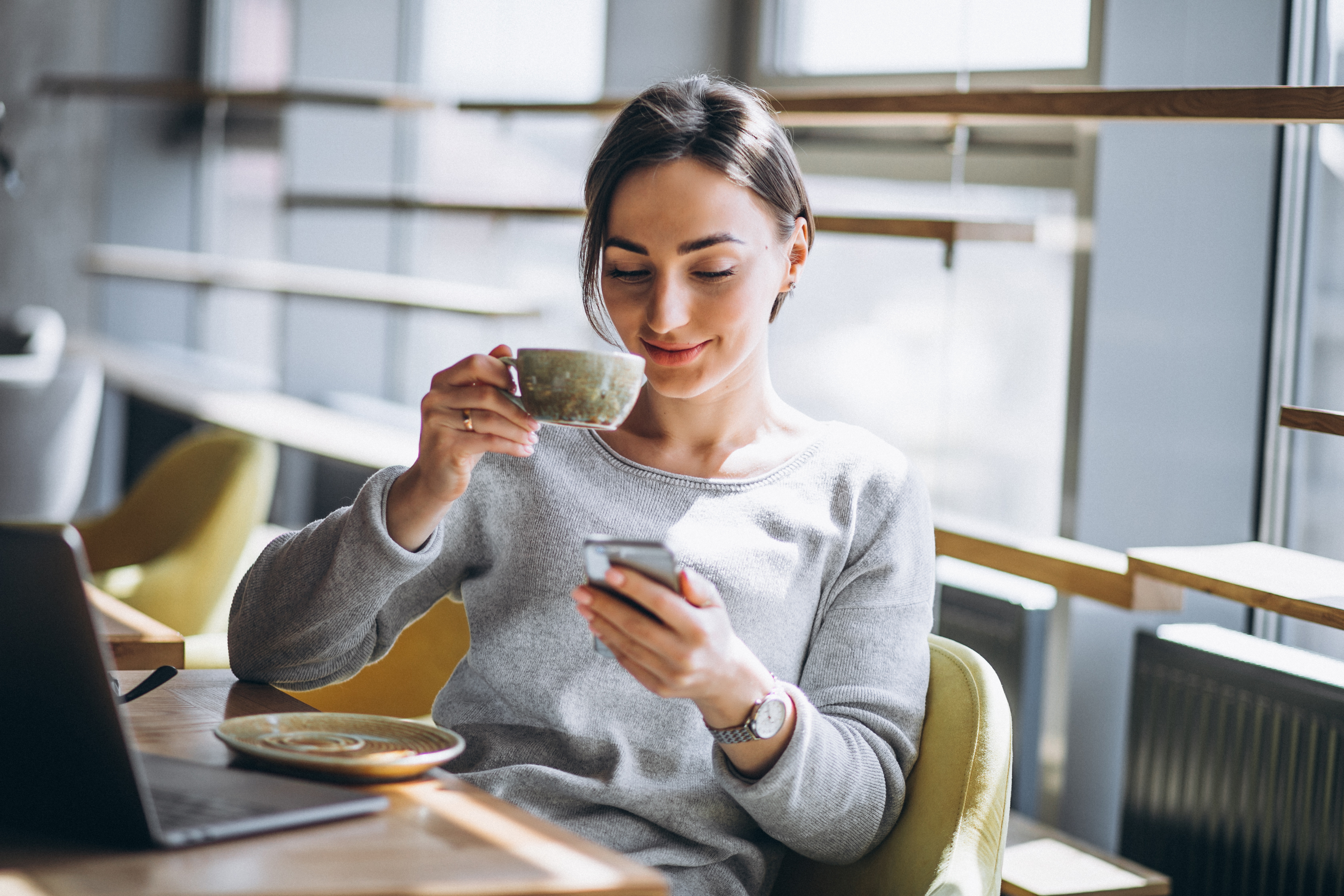 photo woman sitting in a cafe drinking coffee and using mobile phone